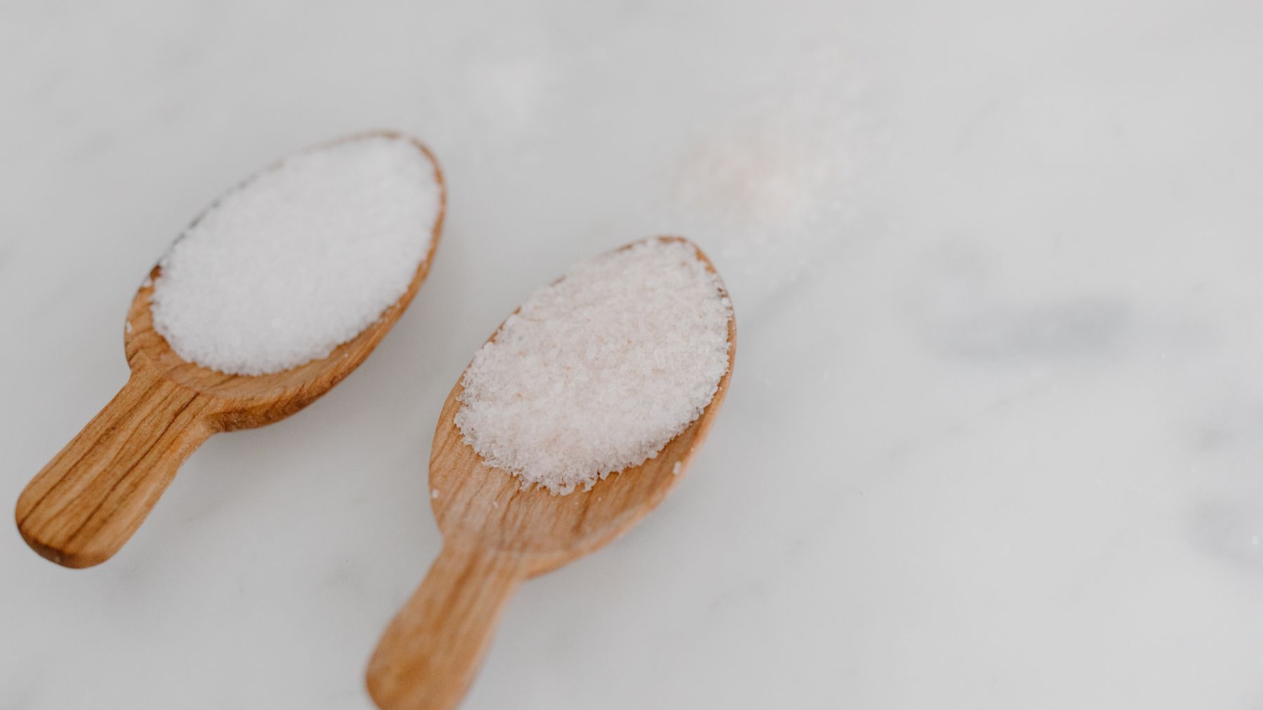 Wooden spoons of artisan sea salt on marble