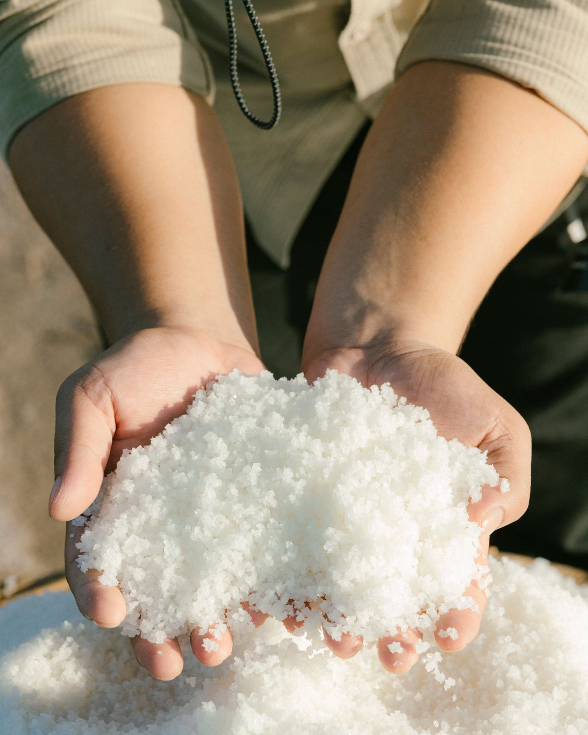 Hands lifting fresh sea salt crystals in the sunlight