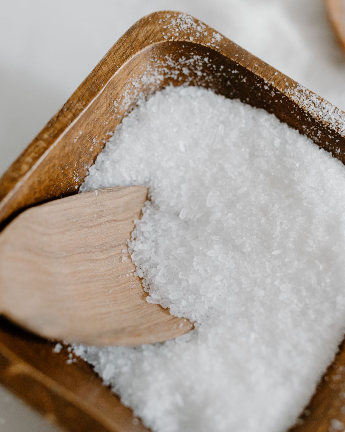 Coarse sea salt in a wooden bowl with a scoop
