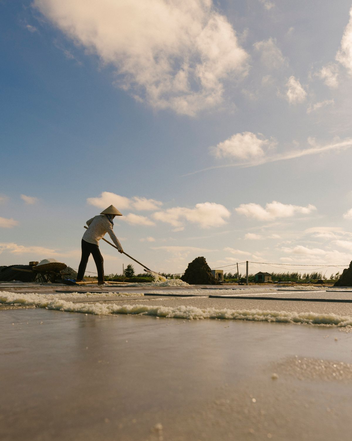A salt maker raking the pans by hand